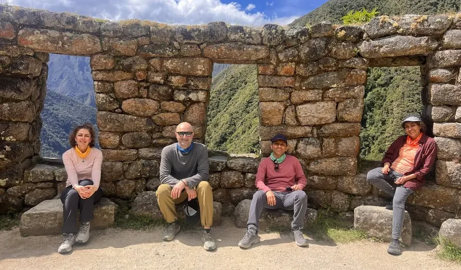 Four hikers resting beside ancient Inca stone walls along the trail to Machu Picchu