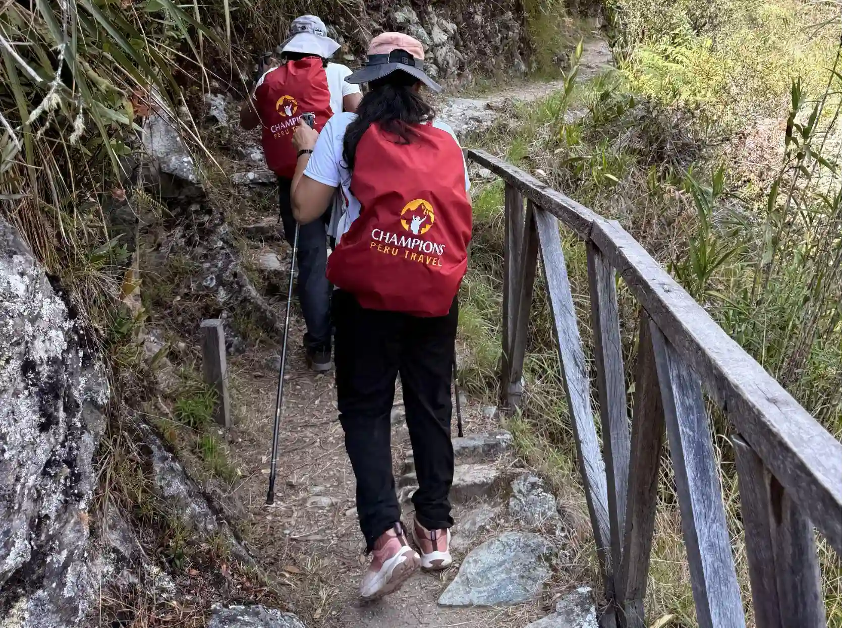 Hikers wearing Champions Peru Travel backpack covers while walking along a narrow Inca Trail path
