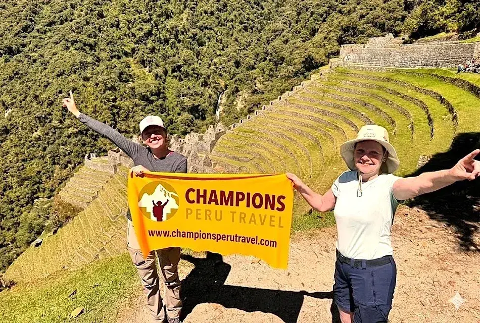 Group of hikers holding a Champions Peru Travel banner at Machu Picchu in Peru