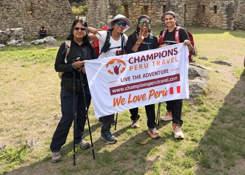 Two travelers holding a Champions Peru Travel banner during a Machu Picchu hiking tour