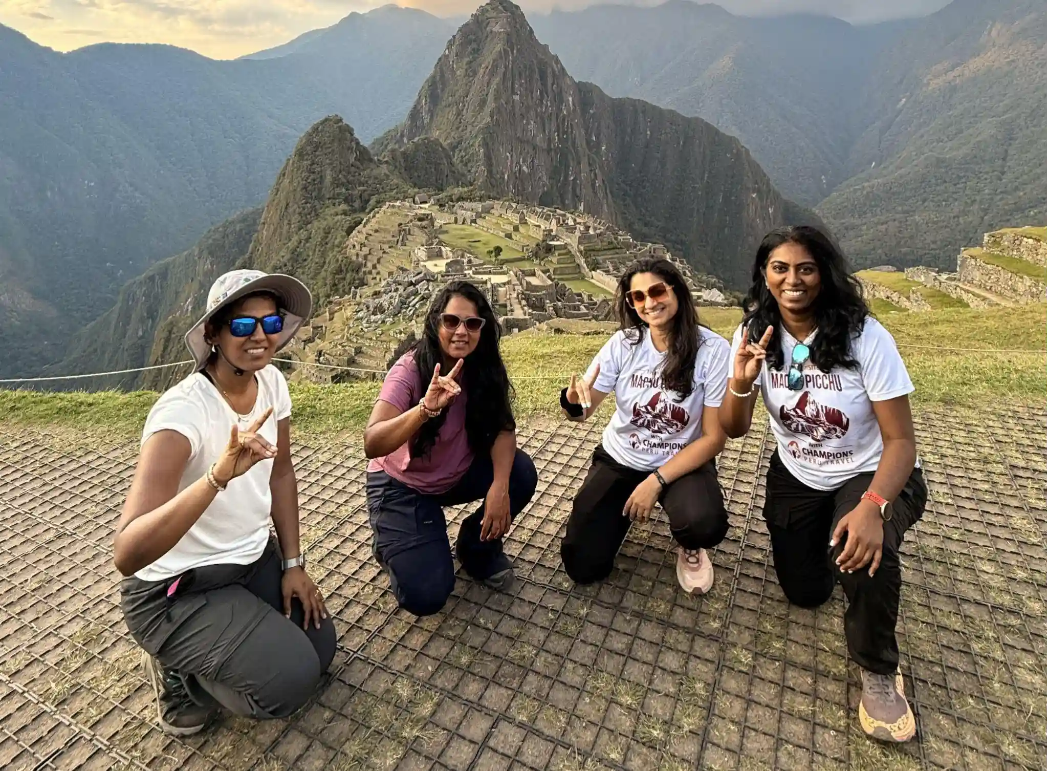 Four women posing at the Machu Picchu viewpoint with Huayna Picchu and the Inca ruins behind them