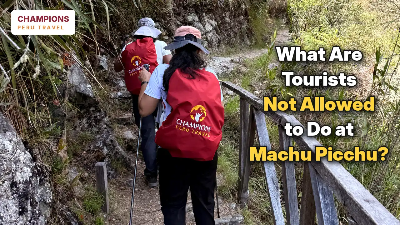 Hikers carrying Champions Peru Travel backpacks while walking along a narrow stone trail toward Machu Picchu.
